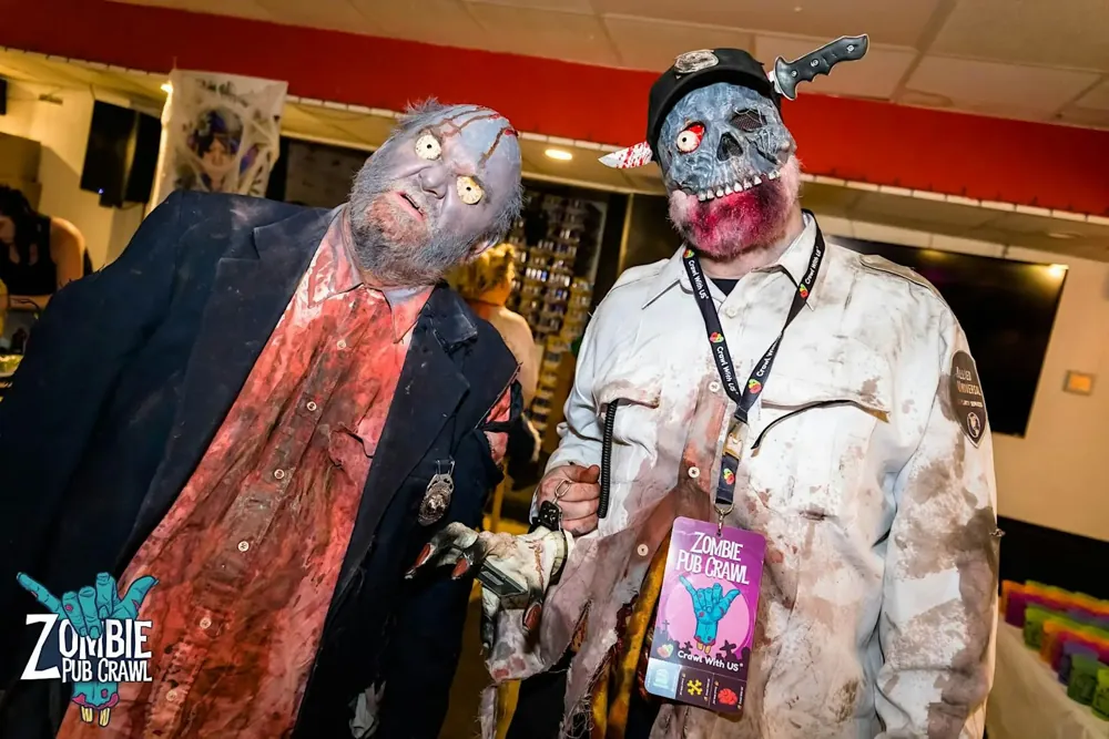 Two crawlers in full zombie makeup and masks with an official Zombie Pub Crawl badge