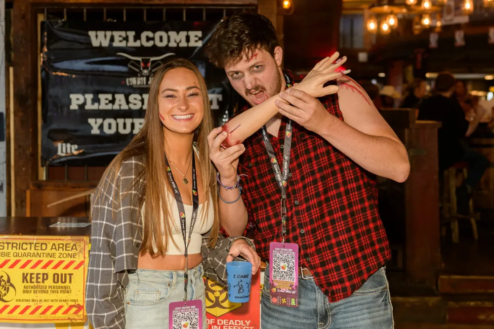 Two crawlers with a severed arm prop at the quarantine-zone check-in of the Zombie Pub Crawl