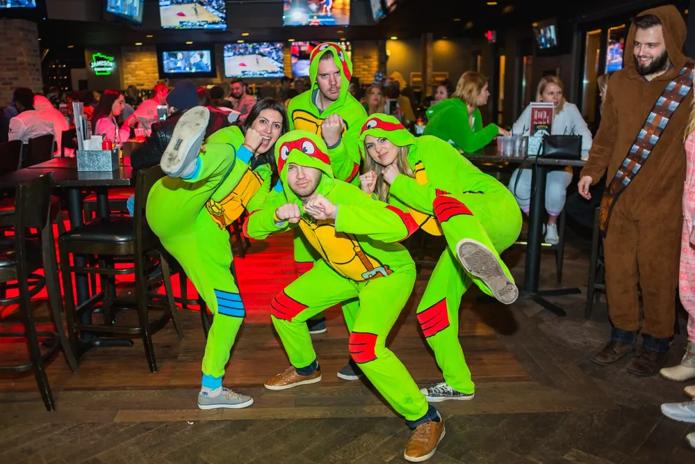 Group of friends in onesies at a participating bar on the Onesie Bar Crawl